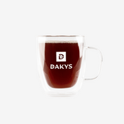 Glass cup with Dakys performance drink – dark infusion made from premium Darjeeling, served in a modern cup with Dakys logo.”