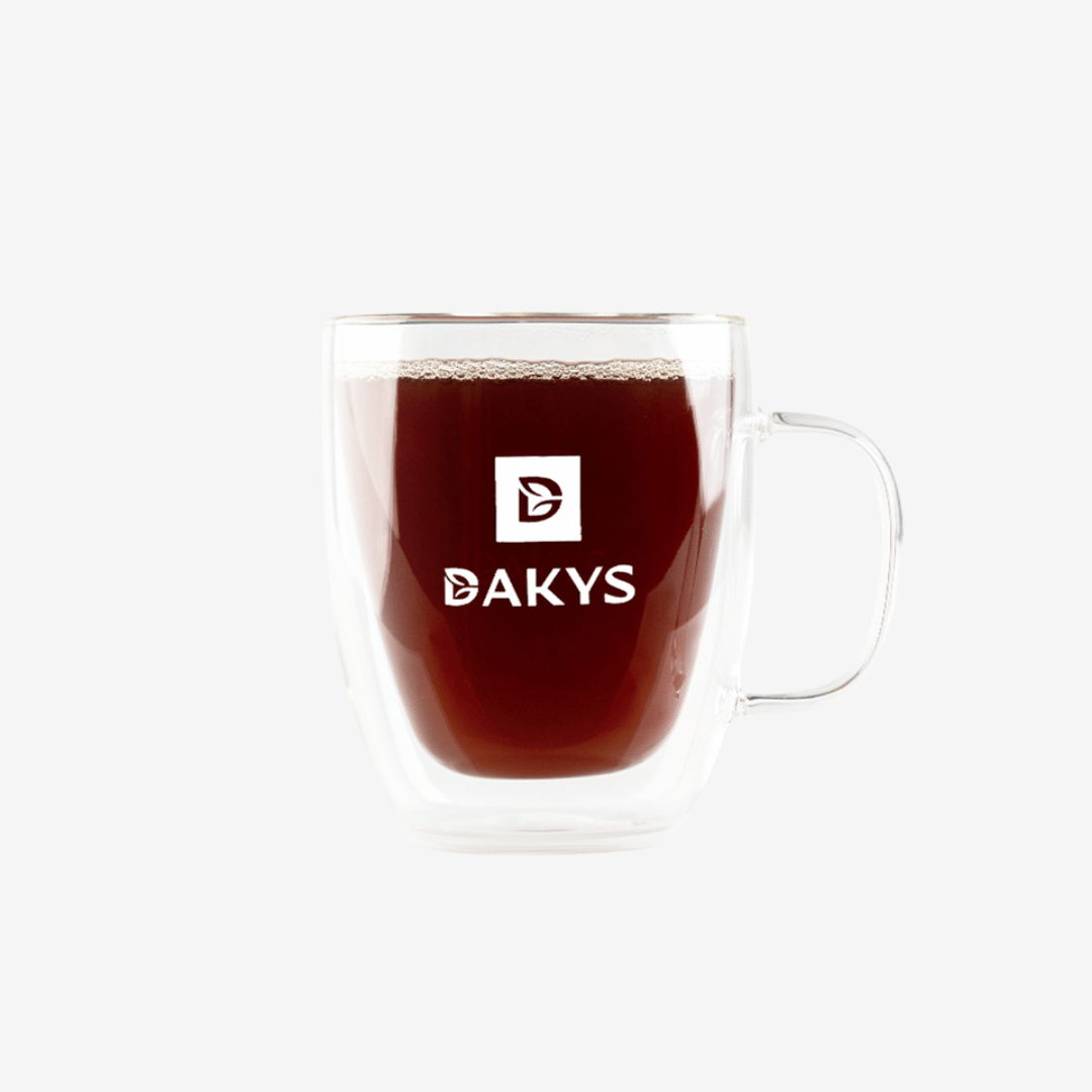 Glass cup with Dakys performance drink – dark infusion made from premium Darjeeling, served in a modern cup with Dakys logo.”