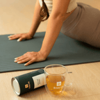 Woman stretching on a yoga mat with Dakys Relax Mind drink and performance drink paper tin – a calm wellness moment with natural recovery support.”