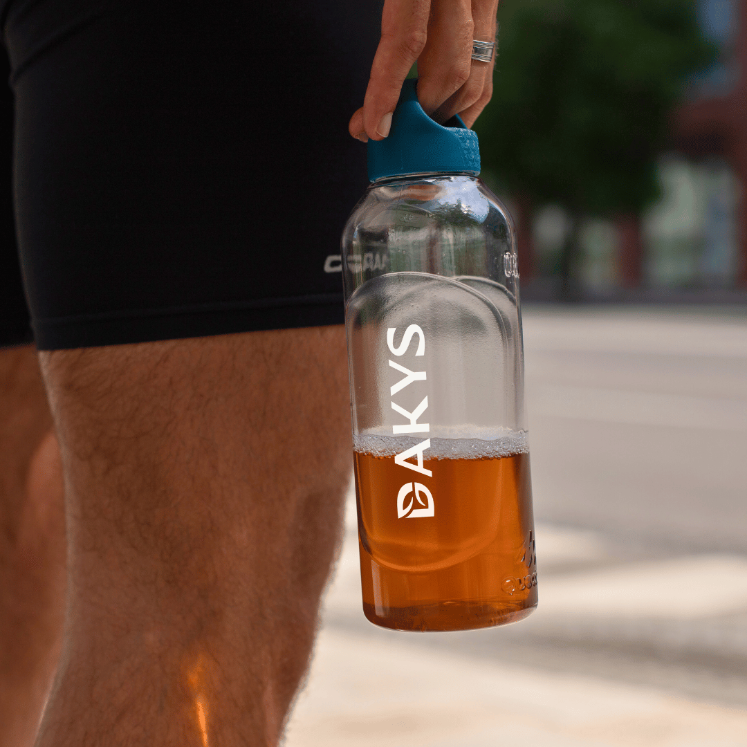 Close-up of a runner holding a bottle filled with Dakys ultra-clean performance drink — clean fuel for high-performers on the move.